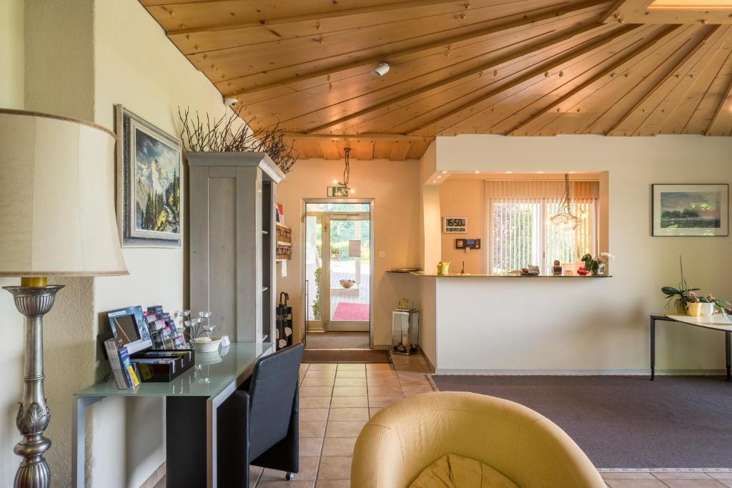 sala de estar con techos de madera, mesa y sillas en Hotel Berghof Amaranth, en Wilderswil