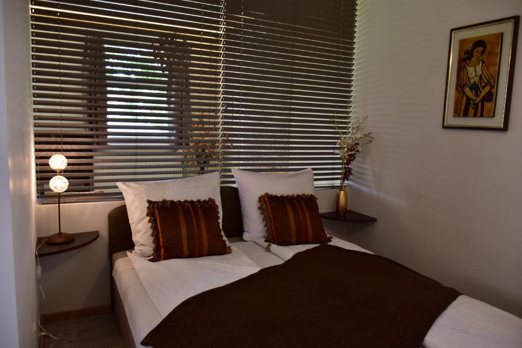 um quarto com uma cama com almofadas e uma janela em Villa Therme Hévíz em Hévíz