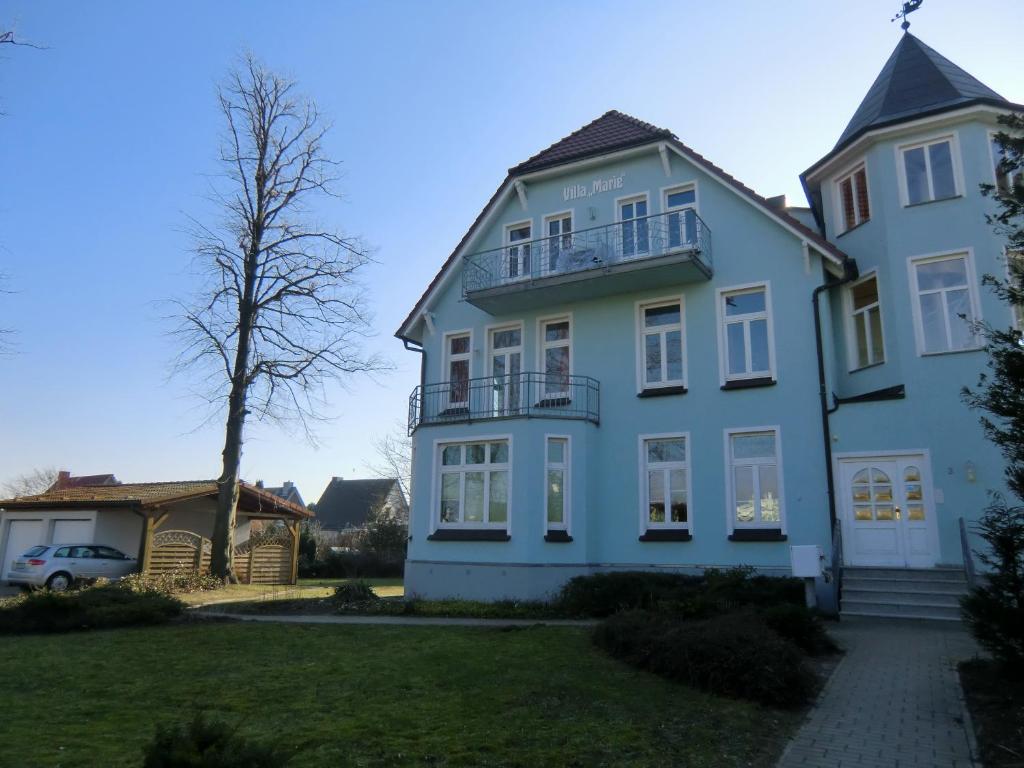 a large white house with a tree in the yard at Ferienwohnung Ostseeglück in der Villa Marie in Kühlungsborn