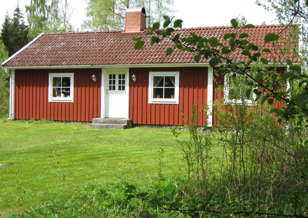 a red house with a white door in a yard at Tildas Urshult in Urshult