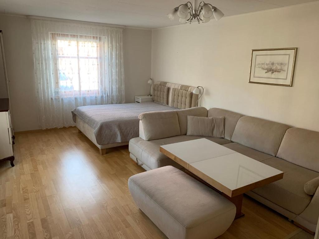 een woonkamer met een bank en een bed bij Baltas apartamentas in Juodkrantė
