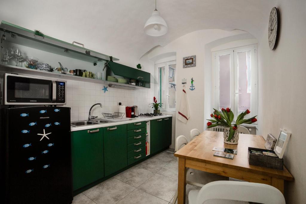 uma cozinha com armários verdes e uma mesa de madeira em La Magnolia, Caressa de mä em Bordighera