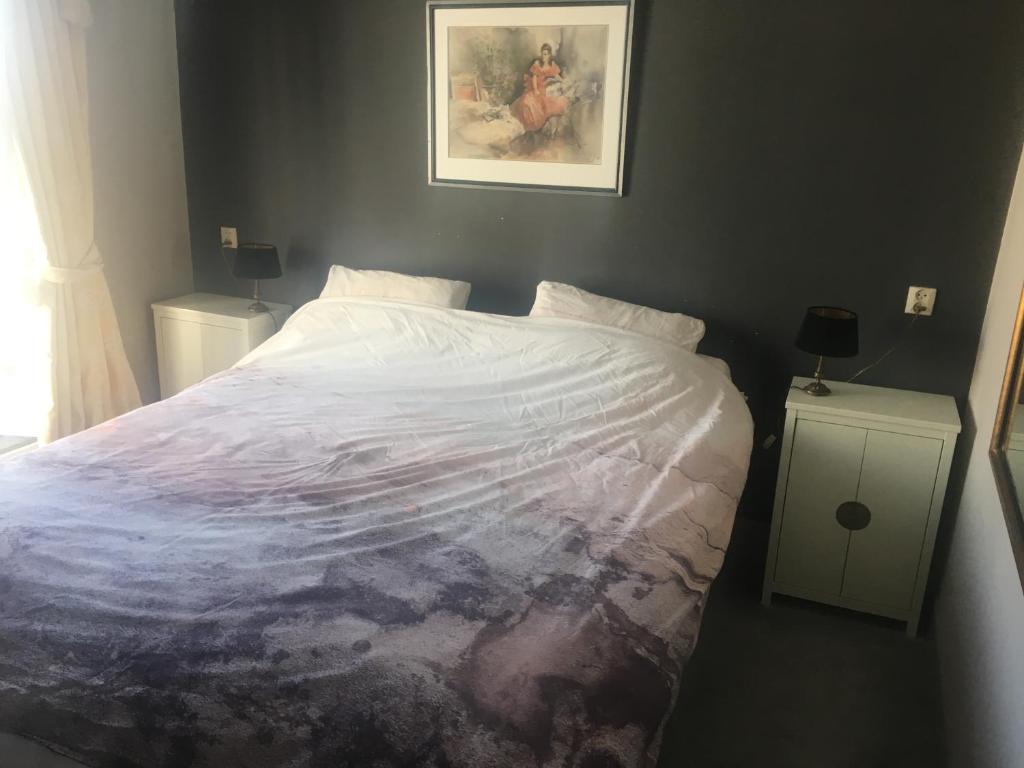 ein Schlafzimmer mit einem großen weißen Bett mit einem Bild an der Wand in der Unterkunft Luc's Place, jaccuzi, waterbed in Zoeterwoude