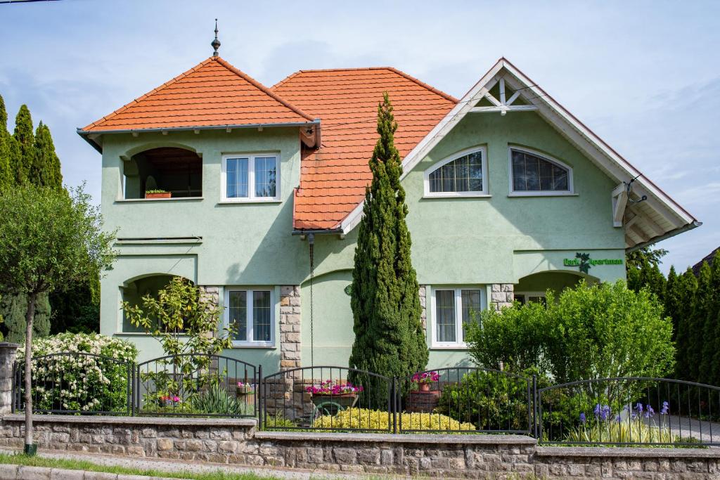 ein grünes Haus mit orangefarbenem Dach in der Unterkunft Park Apartman Hévíz in Hévíz