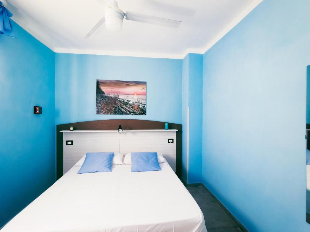 niebieska sypialnia z białym łóżkiem i niebieskimi ścianami w obiekcie Le Sirene Castellabate w mieście Santa Maria di Castellabate