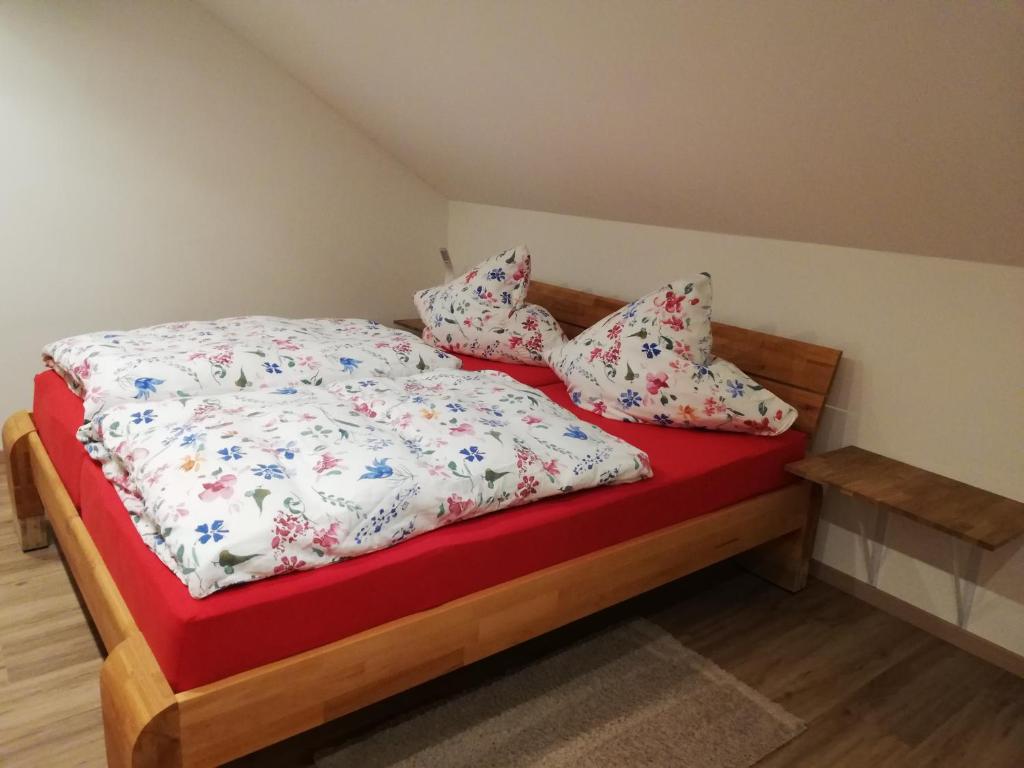 um quarto com uma cama com um cobertor vermelho e almofadas em Emmerich s neu errichtete DG-Wohnung em Bad Wildungen