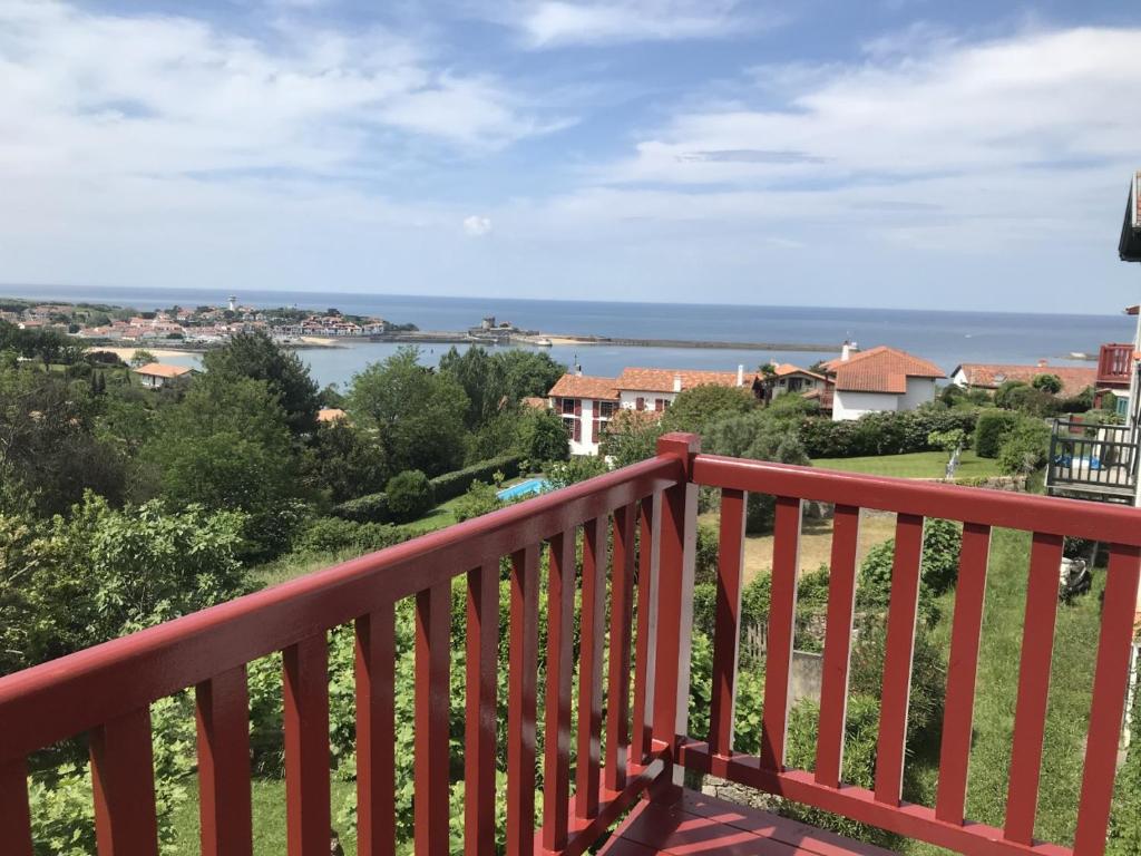 un balcón de madera roja con vistas al agua en Chambres d'hôtes Gela Itsasoa Océan en Ciboure