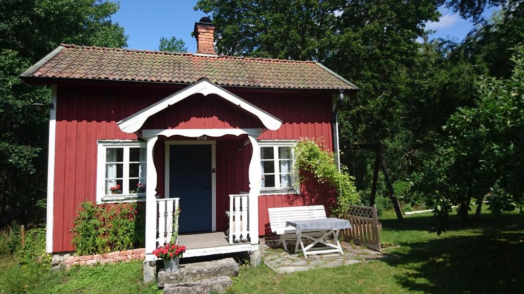 un cobertizo rojo con un banco delante de él en RÖDA STUGAN PÅ SLINKEN en Sala