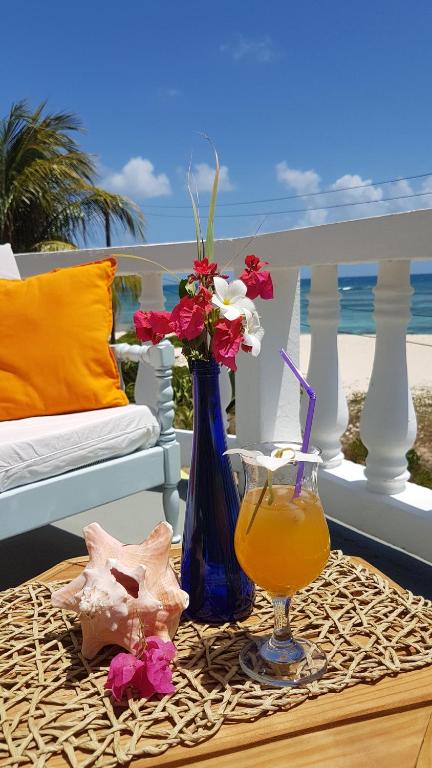 a table with a vase of flowers and a drink at The Islander's Inn in Union Island