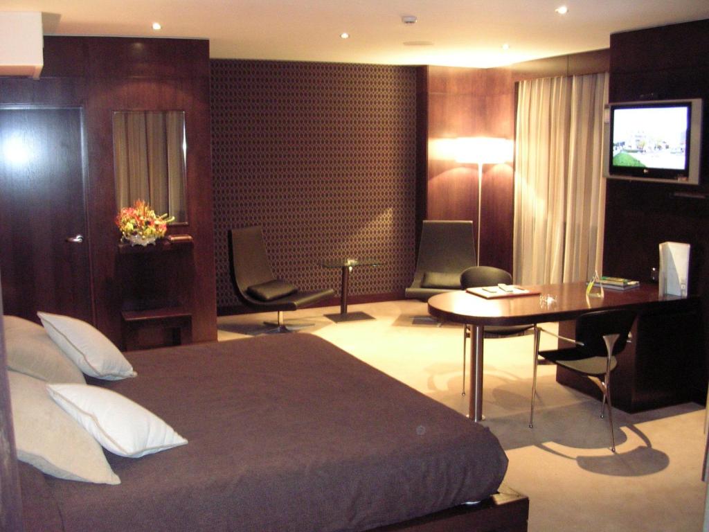 Hotel Francisco II في أورينس: غرفة نوم بسرير ومكتب وطاولة