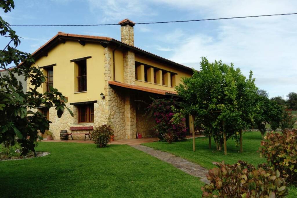 a yellow house with a grass yard at Casa de Aldea La Llosa in Ribadedeva