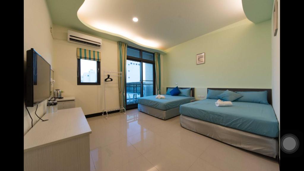 a large room with two beds and a television at Kenting Orange Homestay in Hengchun