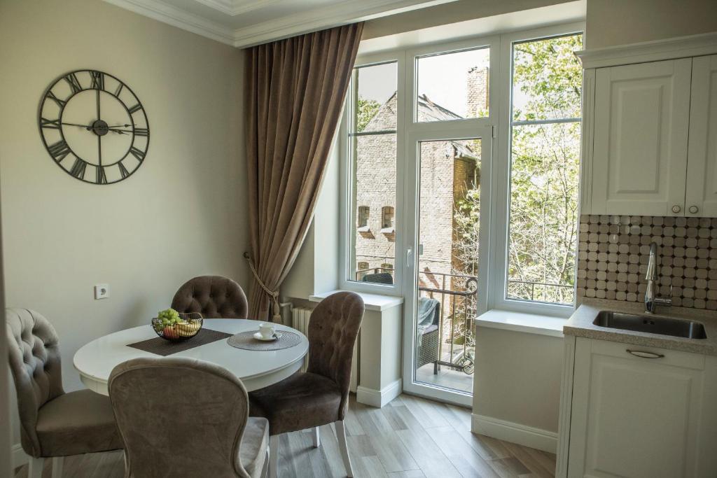 a kitchen with a table and chairs and a clock on the wall at Old Town River Apartments in Klaipėda