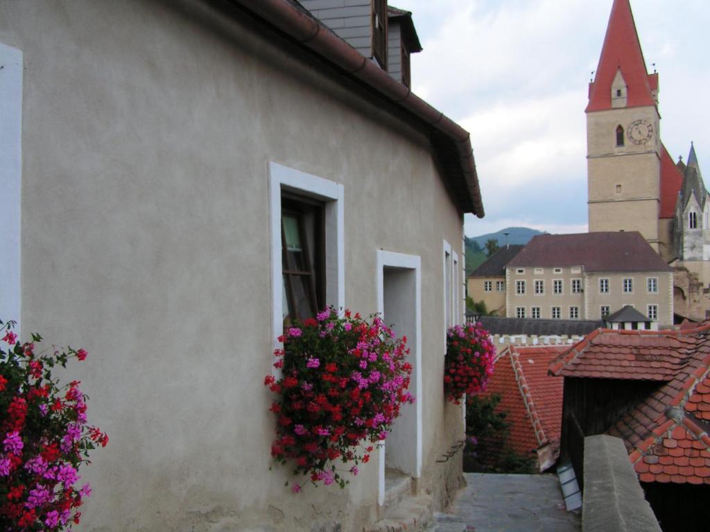 un edificio con flores a un lado. en Apartment Kirchenblick en Weissenkirchen in der Wachau