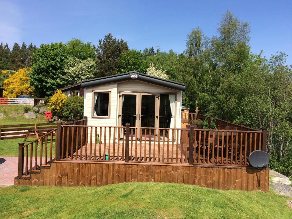 a small cabin with a wooden fence in a yard at Riverbank Lodge in Aviemore