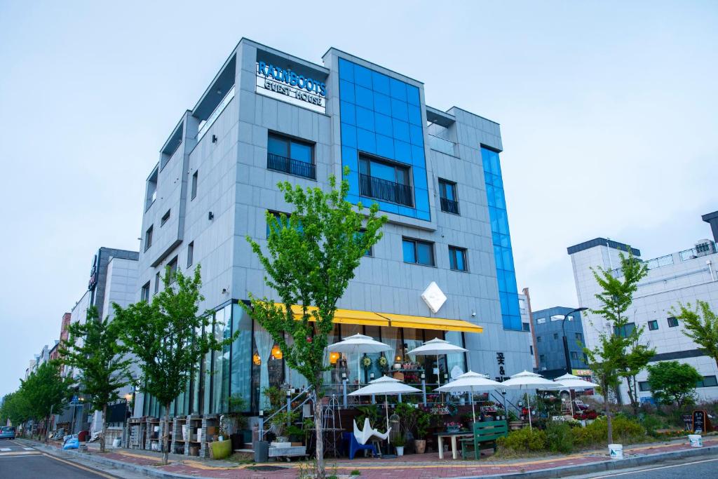 a building with tables and umbrellas in front of it at Rain Boots Guest House in Incheon