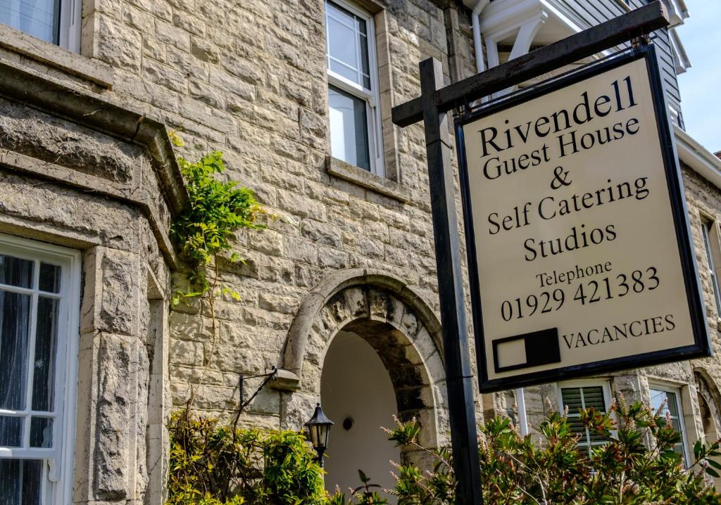 a sign in front of a brick building at Rivendell Holiday Studios & Suite in Swanage