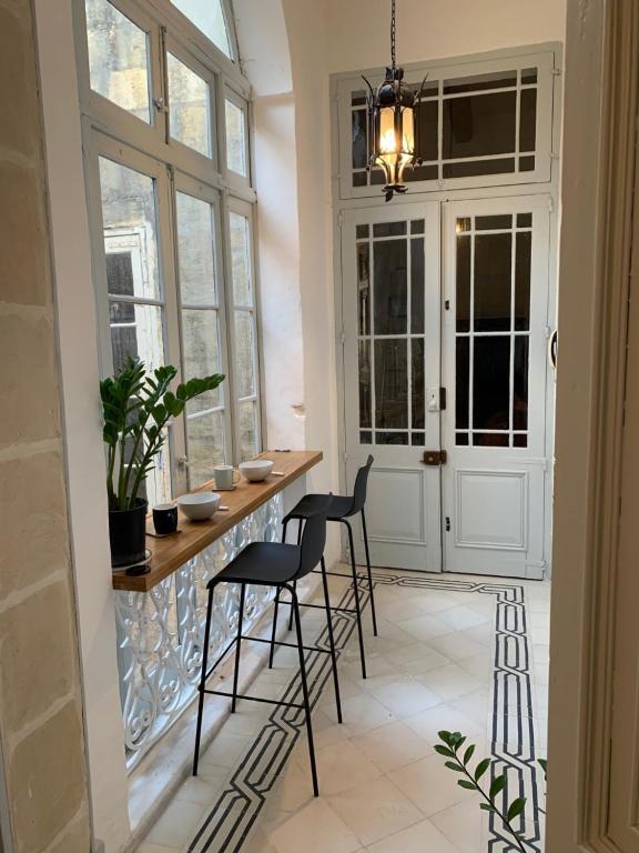 una cocina con una barra con sillas y ventanas en Luxury Valletta Apartment en La Valeta