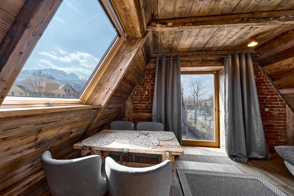 a dining room with a table and chairs and a large window at HEL in Zakopane
