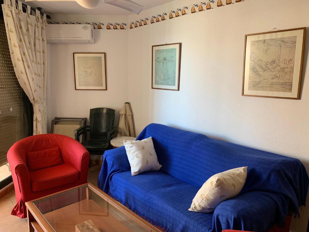 a living room with a blue couch and a red chair at Apartamento Zahara in Zahara de los Atunes