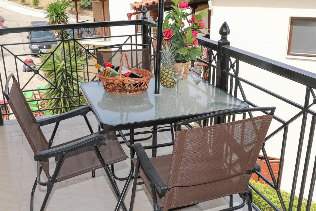 y balcón con mesa de cristal y sillas. en Chrissomallis Apartments, en Skiathos