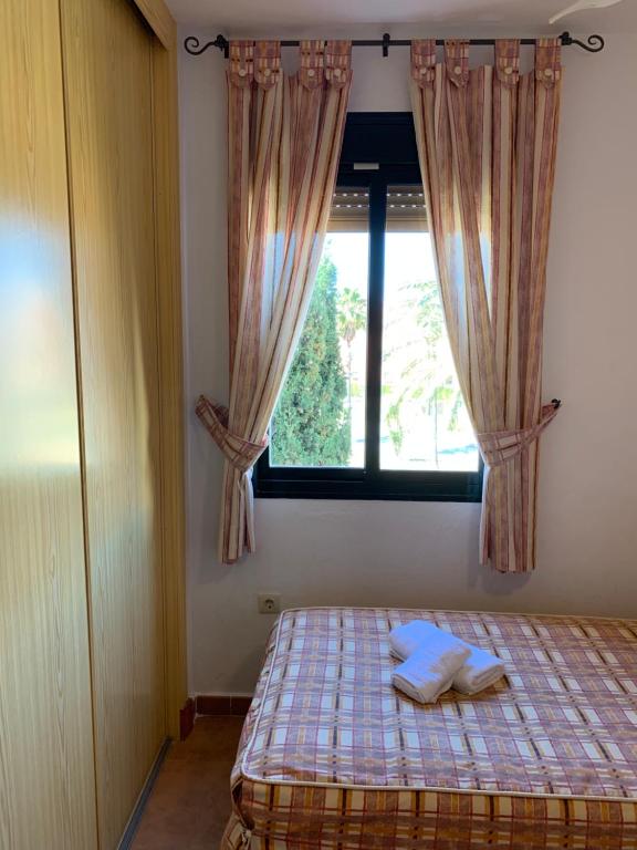 a bedroom with a bed and a window with curtains at Apartamento Zahara in Zahara de los Atunes
