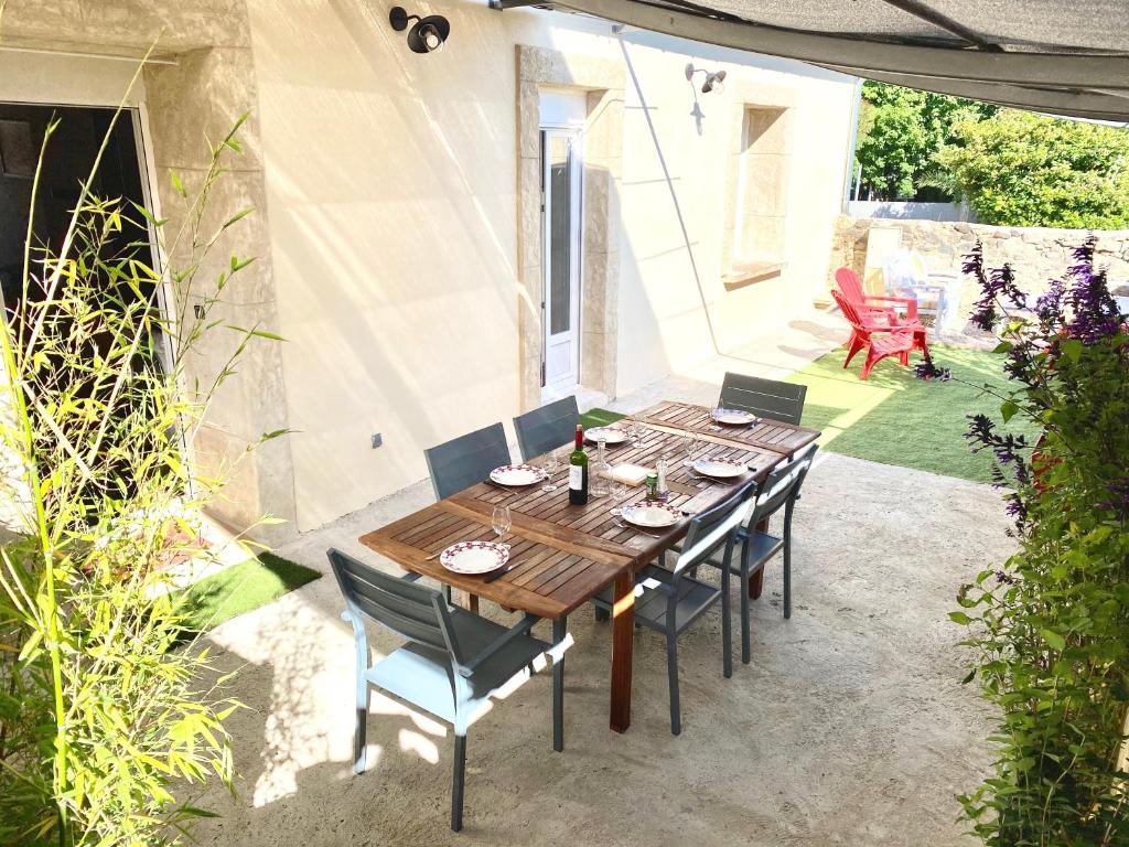 a wooden table and chairs on a patio at Le Mazet du Petit Chemin in Caux