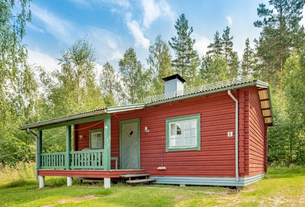 una casita roja con un porche en el bosque en Ekesberget Stugby stuga 6 en Ekshärad