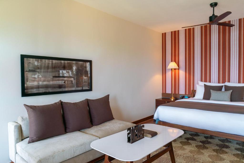 a hotel room with a bed and a couch at Cinnamon Bentota Beach - Signature Selection in Bentota