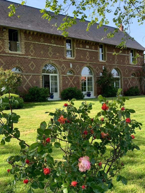 a brick house with roses in front of it at La Grange in Saint-Aubin-sur-Scie