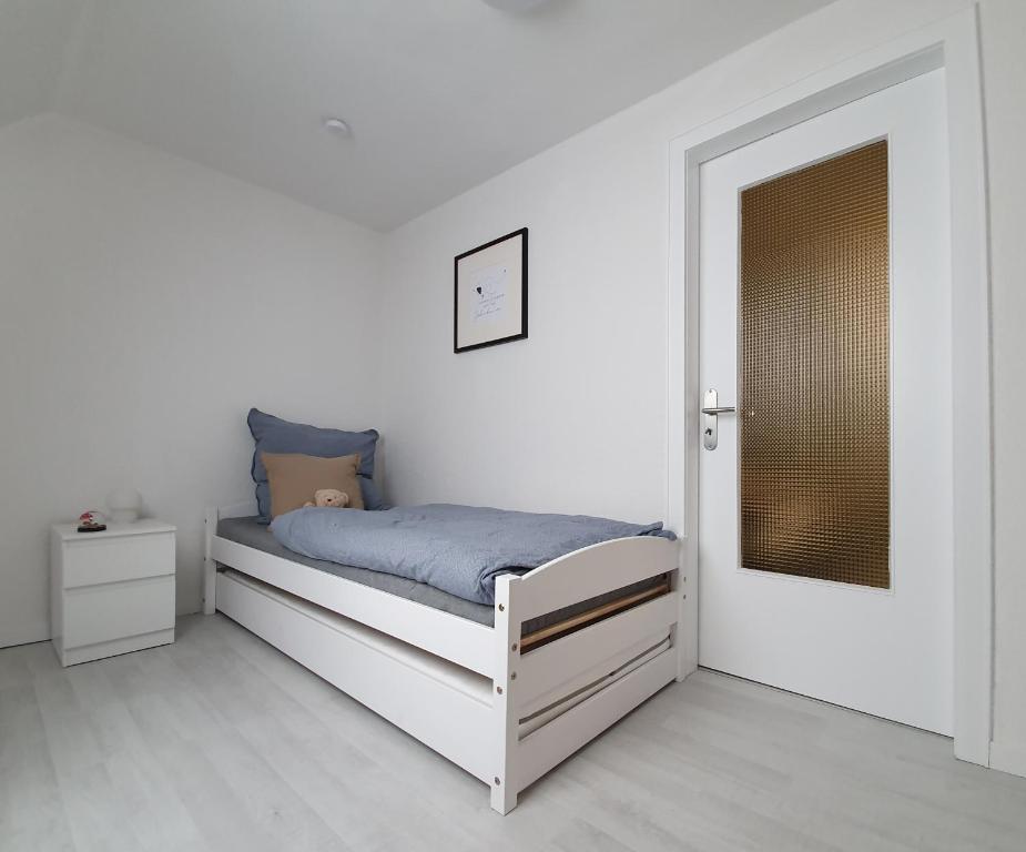 a white bedroom with a bed and a door at Ferienhaus Calmont in Bremm