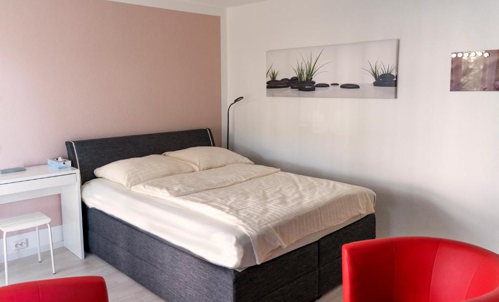 a bed in a room with two red chairs at Ferienwohnung Dennis in Lörrach