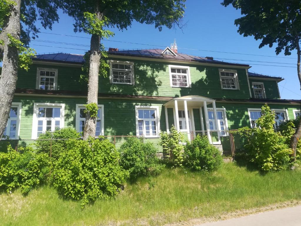 uma casa verde com janelas brancas e arbustos em Zielony Zakątek em Krynki