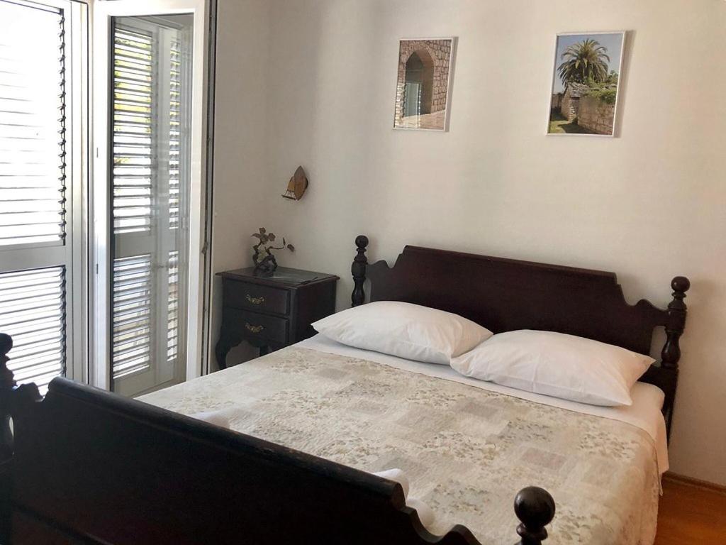 a bedroom with a bed with a wooden headboard and a window at Villa Šolta in Rogač