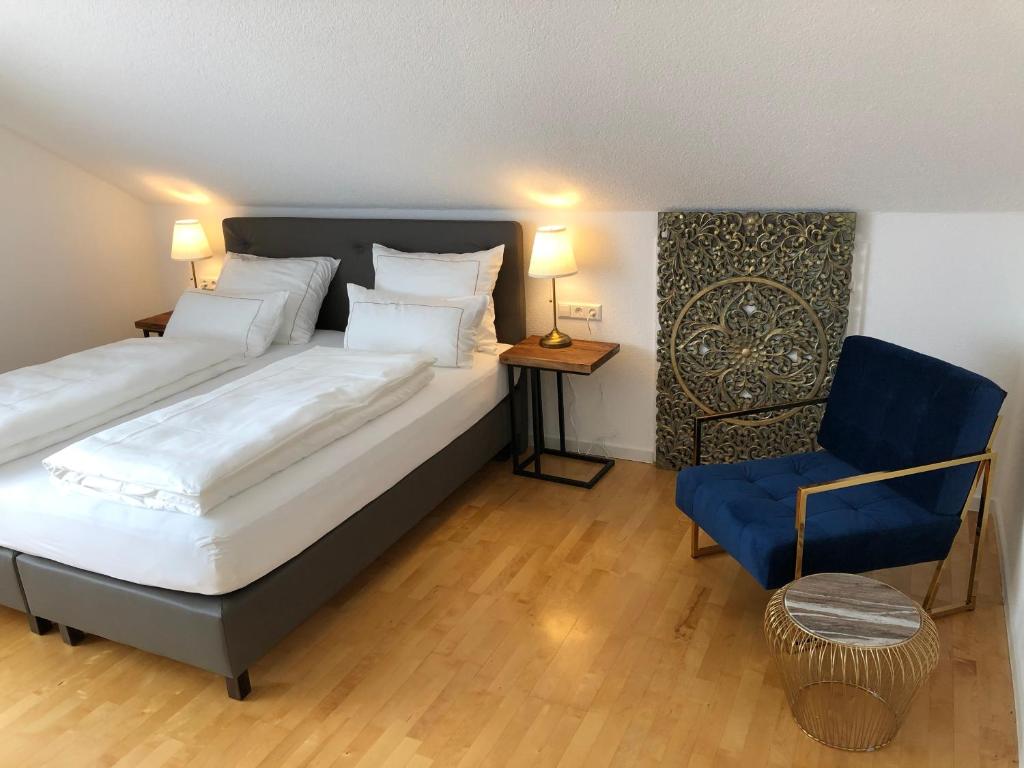 una camera con un grande letto e una sedia blu di City Apartments FN L7 KLIMATISIERT-mit Küche a Friedrichshafen