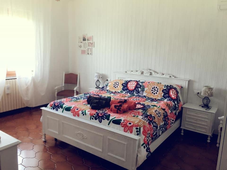 a bedroom with a white bed with a floral bedspread at Villa Sofia in Pramaggiore