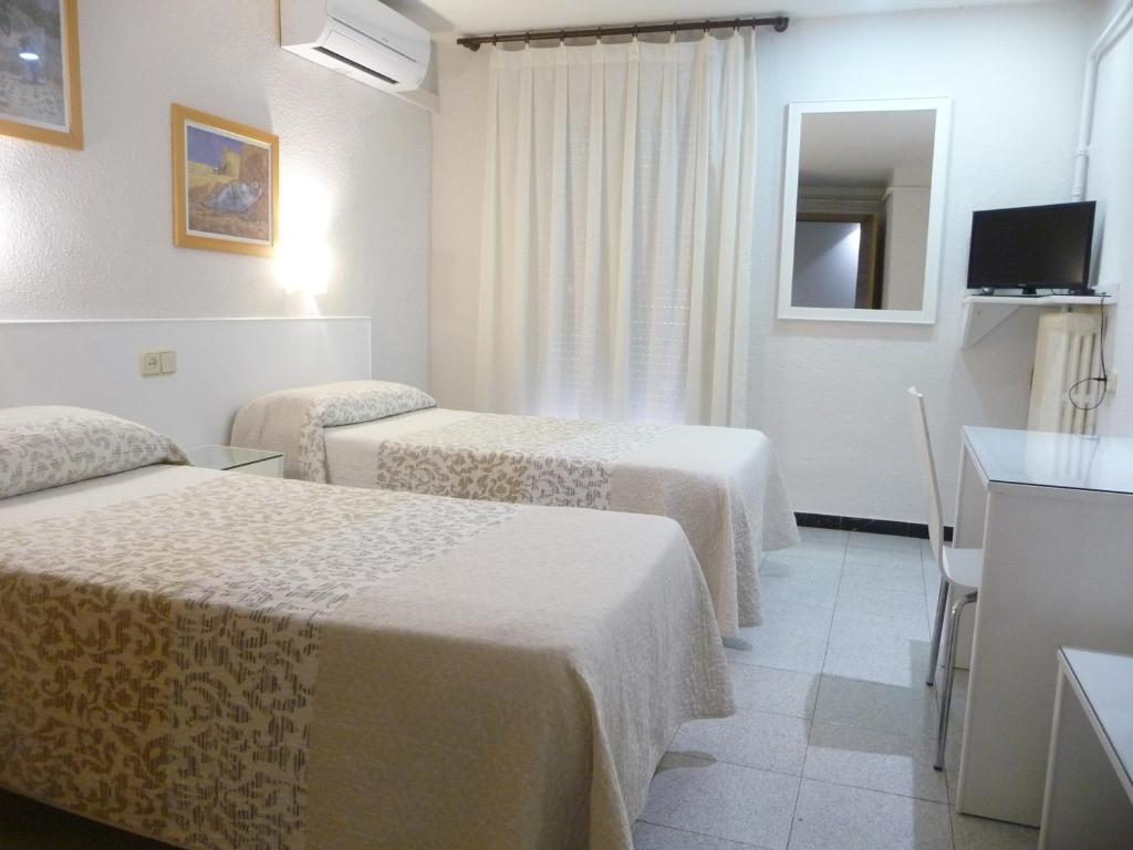 Habitación de hotel con 3 camas y TV en Hotel Goya, en Lleida