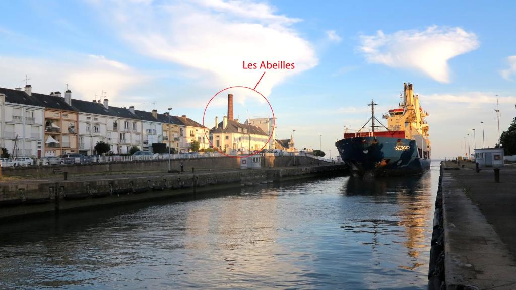 un barco está atracado en un río junto a los edificios en Les Abeilles en Saint-Nazaire