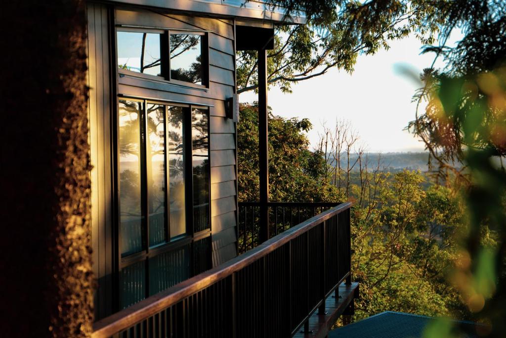 een huis met een balkon met uitzicht op de oceaan bij Rainforest Gardens - Luxury Hillside Accomodation with Views to Bay & Islands in Mount Cotton