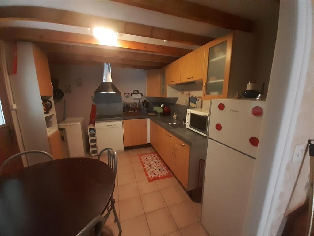 a kitchen with a white refrigerator and a table at Chalet dans village in Saint-Maurice-en-Trièves