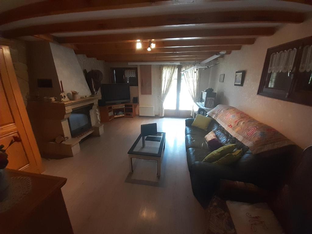 a living room with a couch and a tv at Chalet dans village in Saint-Maurice-en-Trièves