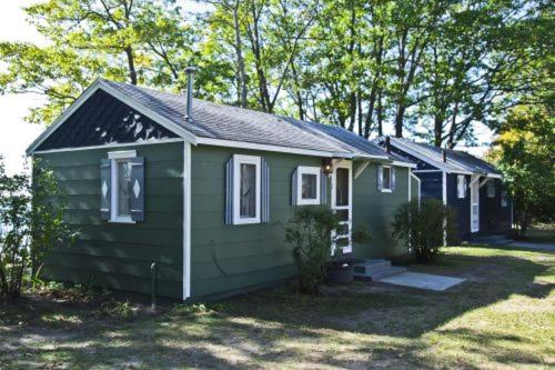 a small green house in a yard with trees at Cabin #1 - Cedar Village cabin in Carp Lake