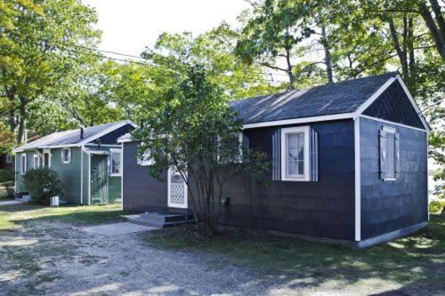 Cabin #2 - M Den cabin في Carp Lake: منزل أسود صغير أمامه شجرة