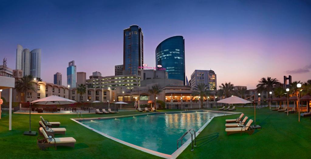 a large swimming pool with a city skyline in the background at Crowne Plaza Bahrain by IHG in Manama