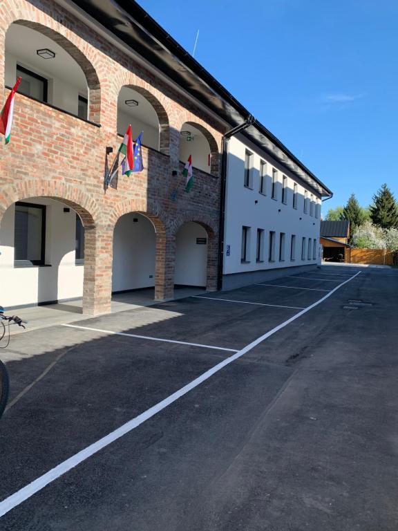an empty parking lot in front of a brick building at M70 Apartmanház in Miskolc