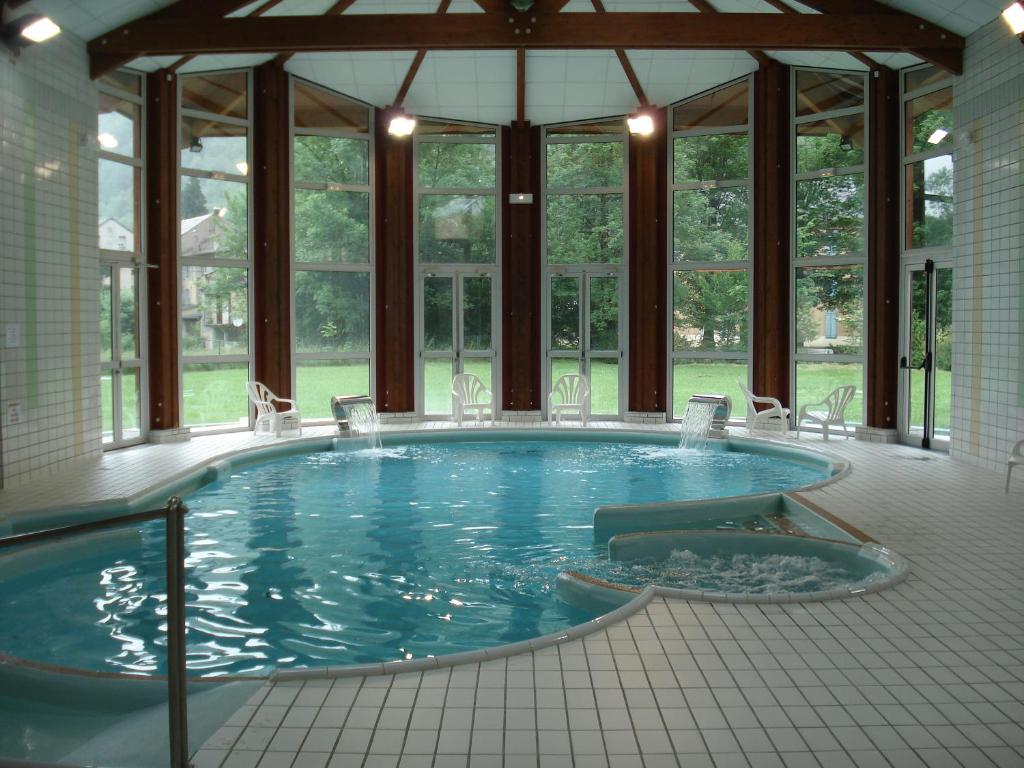 una gran piscina con sillas en una habitación con ventanas en Résidence des 3 Césars, en Aulus-les-Bains