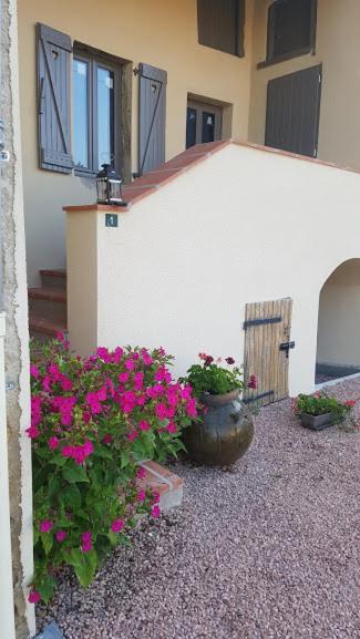 un bâtiment avec des fleurs roses devant lui dans l'établissement Chez Francine La Chenevière, à Saint-Rémy-de-Chargnat
