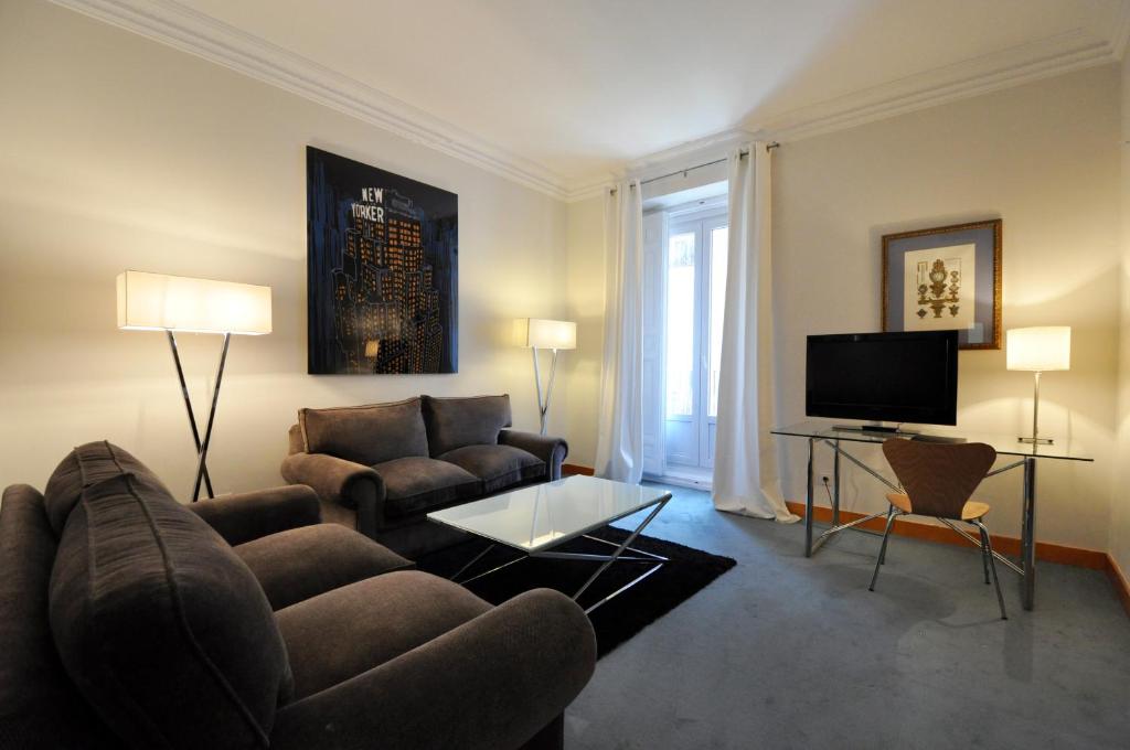 Una sala de estar con un sofá y un televisor. en Suite Prado, en Madrid