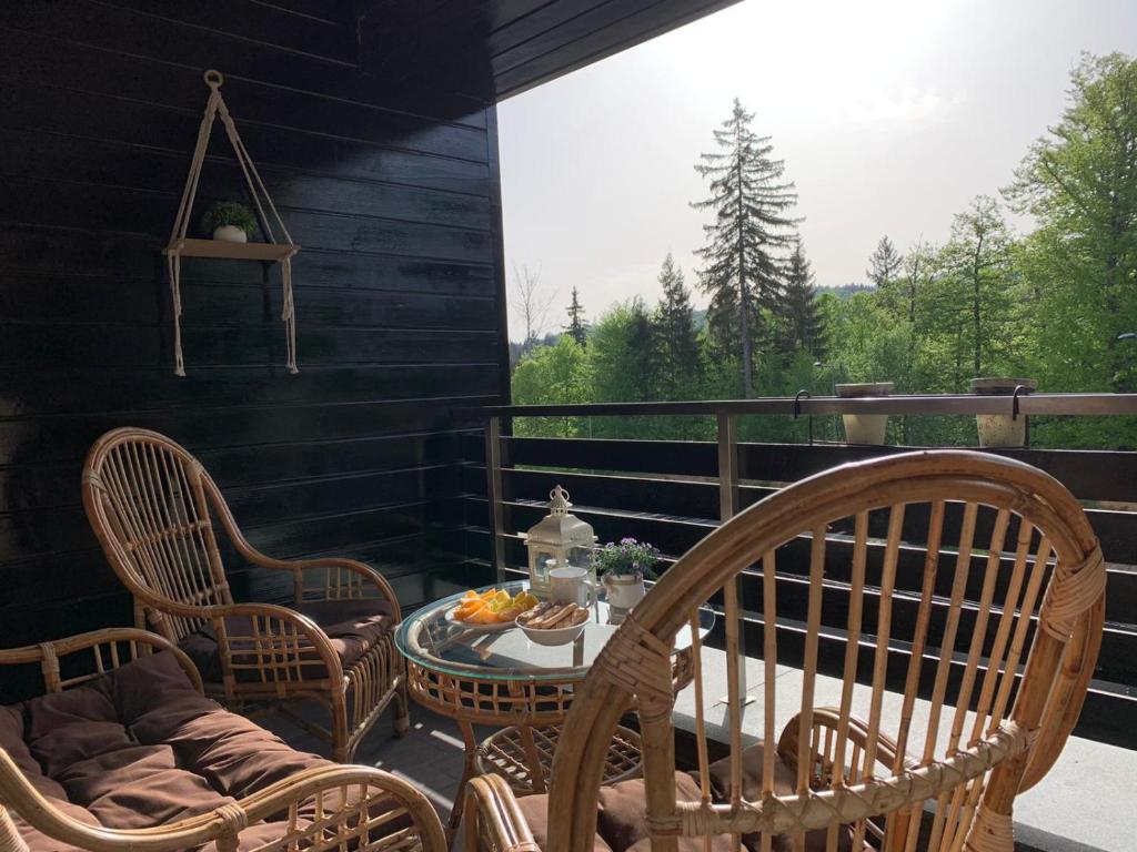 eine Terrasse mit Stühlen, einem Tisch und einem Fenster in der Unterkunft TIAM Apartment Poiana Brașov D117, 3 rooms, 3 terraces, 3 bathrooms in Poiana Brașov