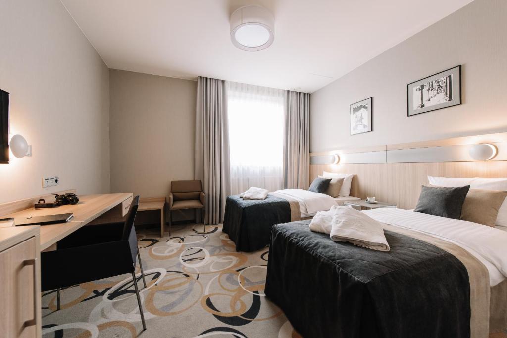 um quarto de hotel com duas camas e uma secretária em Krowodrza Centrum Konferencyjno - Hotelowe em Cracóvia